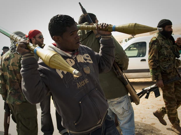 A Libyan rebel carries rockets