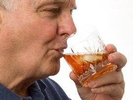 Senior male drinking spirits from a tumbler.