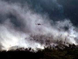 A helicopter flies over the Waldo Canyon fire as it continues to burn June 27, 2012, in Colorado Springs, Colo.