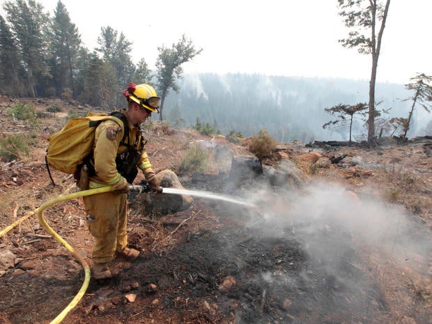 Firefighter Josh Gillick hoses down a hot spot of the Ponderosa Fire near Viola, Calif., Monday, Aug. 20, 2012. More than 1,400 fire fighters are battling the fire that has destroyed seven homes, burned 23 square miles.
