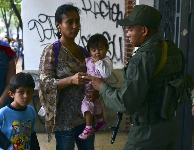 People line up to cast their vote at the Andres Bello polling station, in Caracas on April 14, 2013. Venezuelans headed to the polls on April 14 to elect Hugo Chavez's successor, with his political heir, Nicolas Maduro, hoping to continue his socialist revolution and rival Henrique Capriles vowing change in the divided nation.