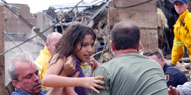 A child is pulled from the rubble of the Plaza Towers Elementary School in Moore, Okla., and passed along to rescuers Monday, May 20, 2013. A tornado as much as a mile (1.6 kilometers) wide with winds up to 200 mph (320 kph) roared through the Oklahoma City suburbs Monday, flattening entire neighborhoods, setting buildings on fire and landing a direct blow on an elementary school.