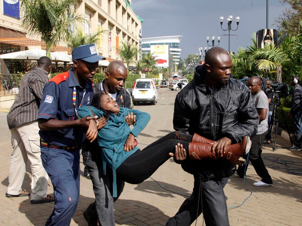 A security officer helps a wounded woman outside the Westgate Mall in Nairobi, Kenya, Sept. 21, 2013, after gunmen threw grenades and opened fire during an attack that left multiple people dead and dozens wounded.
