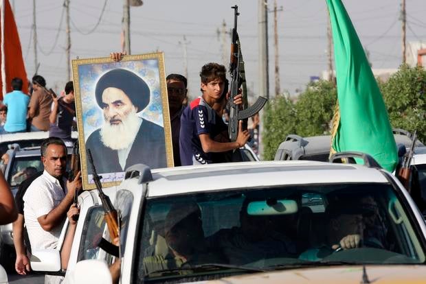 Volunteers who have joined the Iraqi Army to fight against predominantly Sunni militants carry weapons and a portrait of Grand Ayatollah Ali al-Sistani during a parade in Baghdad's Sadr City