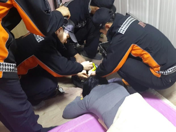 Firefighters try to remove a South Korean woman's hair from a robotic vacuum cleaner at her home