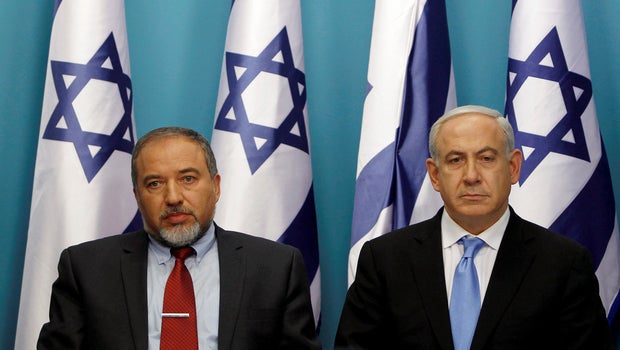 Israel's Prime Minister Benjamin Netanyahu (R) sits next to then-Foreign Minister Avigdor Lieberman