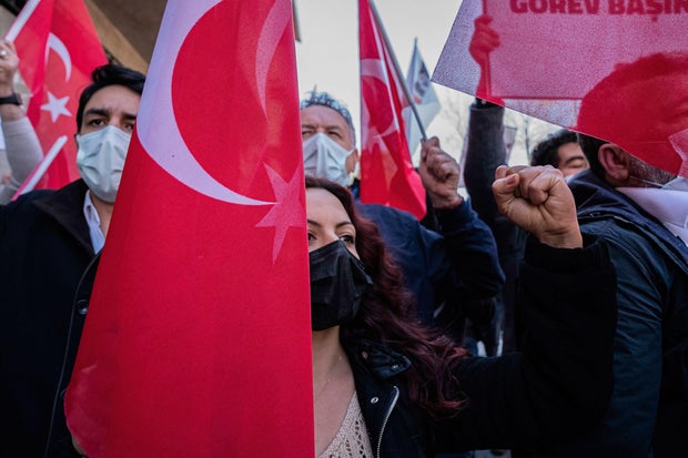 A protester makes a gesture while holding a Turkish flag in