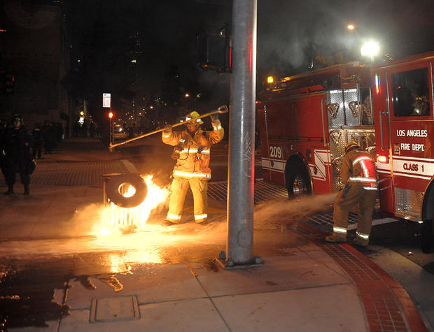 Los Angeles Fire Department firefighters extinguish a trash fire near the Staples Center in Los Angeles on Thursday, June 17, 2010. Crowds of rowdy revelers poured into the streets around Staples Center after Game 7 of the NBA finals rocking cars, setting bonfires and throwing rocks and bottles at officers. 
