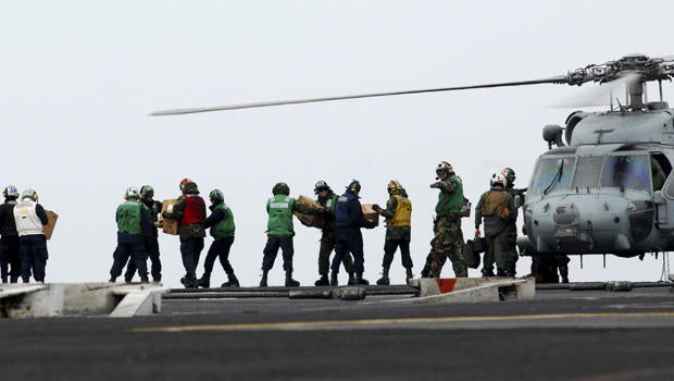 sailors move food and water onto an HH-60H Sea Hawk