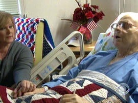 Barbara Stadler, a Veterans Affair employee who volunteers at the hospital's end-of-life program, holds the hand of Korean war vet Richard Murley.