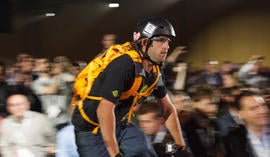 A bicyclist rides down the aisle at Google I/O wearing Project Glass computerized glasses.