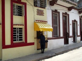 A customer picks up take-out food sold out of a private home's front door in Havana.