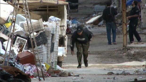 A Syrian ducks while passing through a dangerous part of Baba Amr in Homs, Syria.