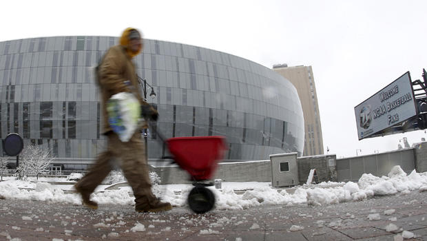 A man spreads salt on the sidewalk across the street from the Sprint Center, Sunday, March 24, 2013, in Kansas City, Mo. The man was preparing for the third round of the NCAA college basketball tournament at the arena after the region received 6-10 inches of snow overnight.