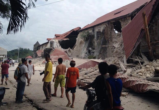 People walk past the damaged Church of San Pedro in the town of Loboc, in the Bohol province of the Philippines, after a major earthquake struck the region
