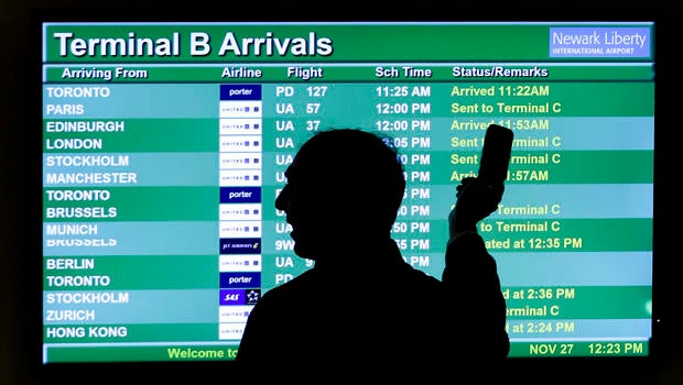 A person points to a screen displaying an airplane travel list while he talks on a phone at Newark Liberty International Airport as travelers get a head start on Thanksgiving Day travel Nov. 27, 2013, in Newark, N.J.