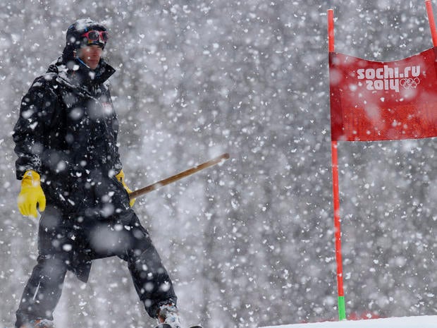A ski course worker waits with a shovel under heavy snow fall just before the start of the second run of the women's giant slalom at the Sochi 2014 Winter Olympics, in Krasnaya Polyana