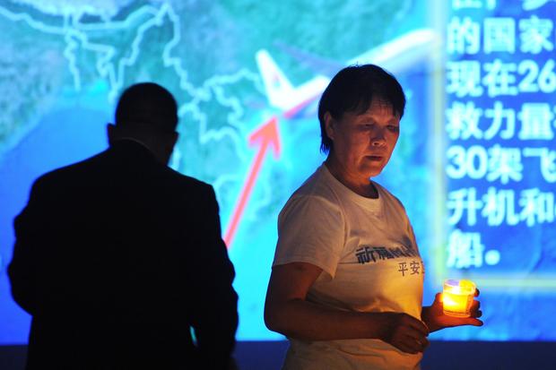 A Chinese relative (R) of passengers on the missing Malaysia Airlines flight MH370 holds a candle as she takes part in a prayer service at the Metro Park Hotel in Beijing