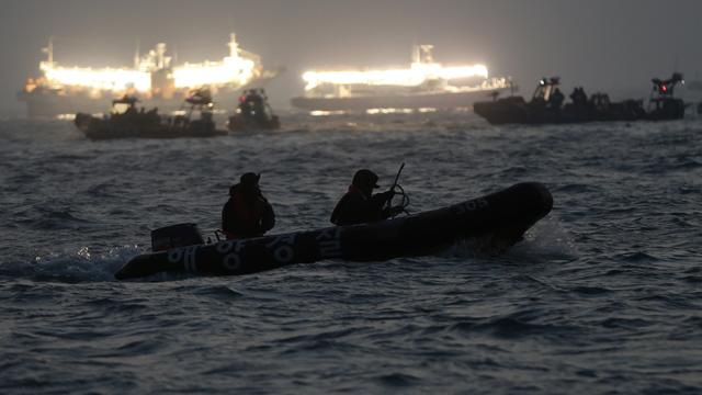 South Korean rescue workers search the area where the capsized passenger ferry Sewol sank, as fishing boats emit light 