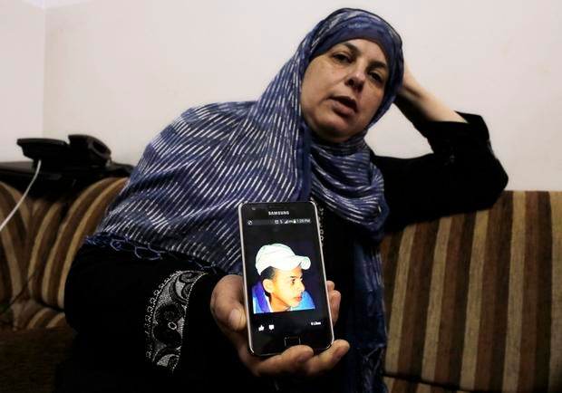 Suha, mother of Mohammed Abu Khudair, shows a picture of her son on her mobile phone at their home in Shuafat