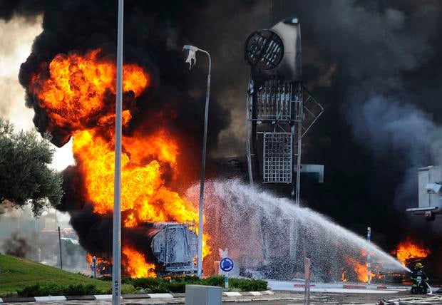 Israeli firefighters extinguish a fire that broke out after a rocket hit a petrol station in the southern Israeli city of Ashdod