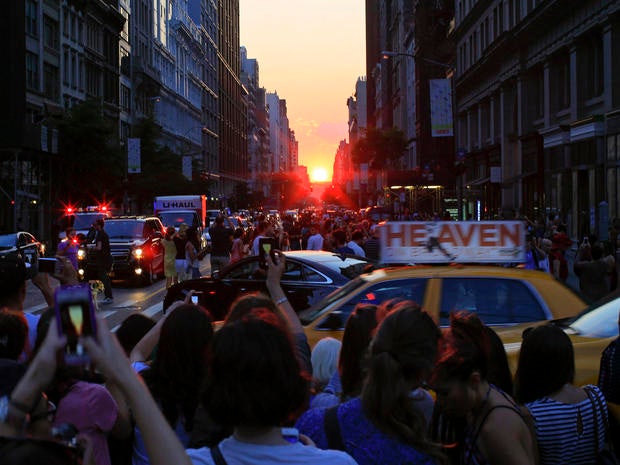 People take pictures at sunset during the bi-annual occurrence of Manhattanhenge in New York July 11, 2014.