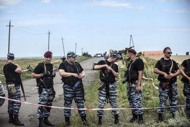 Armed pro-Russian separatists stand guard in front of the crash site of Malaysia Airlines Flight 17 near the village of Grabovo