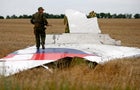An armed pro-Russian separatist stands on part of the wreckage of the Malaysia Airlines Boeing 777 plane July 17, 2014, after it crashed near the settlement of Grabovo in the Donetsk region. 