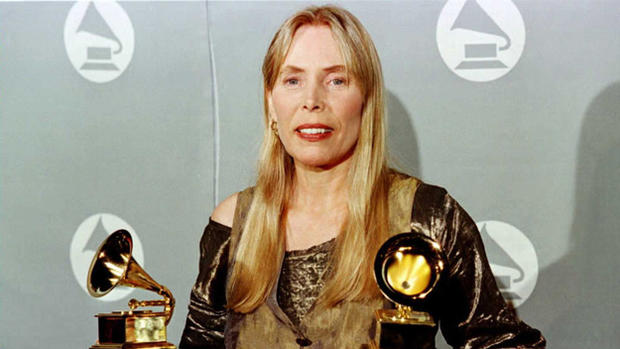 Joni Mitchell smiles as she holds two Grammy Awards at 38th Annual Grammy Awards 28 February in Los Angeles. Mitchell won Grammys for Best Pop Album for "Turbulent Indigo." AFP PHOTO/Jeff Haynes (Photo by Jeff Haynes/Getty Images) 