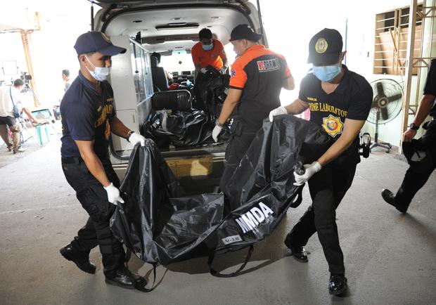 A police forensics team unloads a body bag containing the remains of a victim killed in a fire that gutted a footwear factory in Valenzuela city in suburban Manila