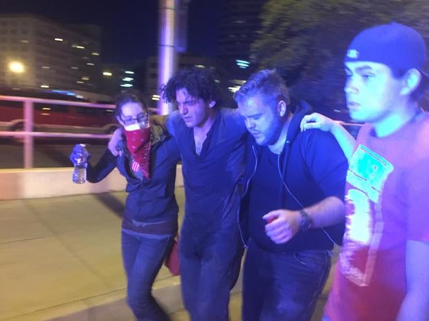 Protesters help a fellow demonstrator who was affected by the smoke and pepper spray used by police to disburse the crowd outside a rally for Donald Trump in Albuquerque on May 24, 2016