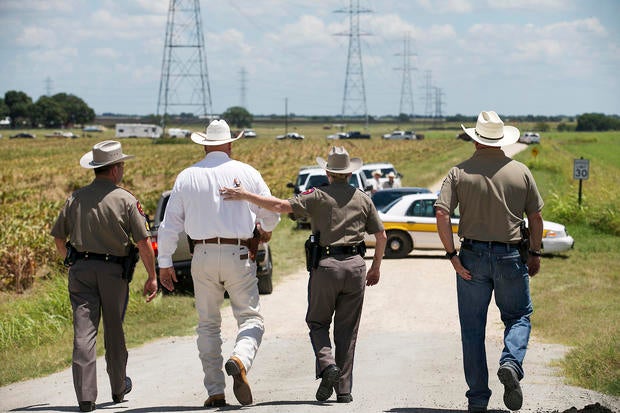 Texas Department of Public Safety Trooper Robbie Barrera, center right, puts her arm around Caldwell County Sheriff Daniel Law as he arrives on the scene of a hot air balloon crash July 30, 2016, near Lockhart, Texas, causing what authorities described as a "significant loss of life."