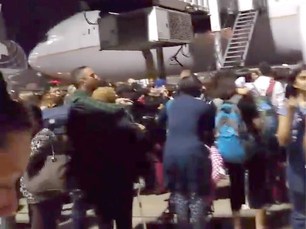 Passengers stand on a tarmac at Los Angeles International Airport late on Aug. 28, 2016, after at least one terminal was evacuated following unconfirmed reports of an active shooter in the building