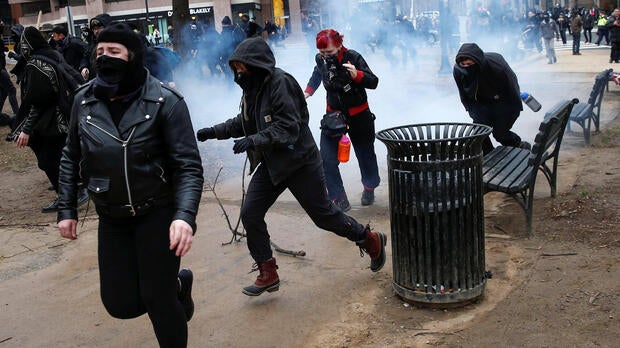 Activists race after being hit by a stun grenade while protesting against President Trump on the sidelines of the inauguration in Washington Jan. 20, 2017.