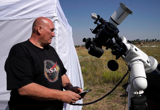 Rick Roty works with his telescope in a designated eclipse viewing area in a campground near Guernsey