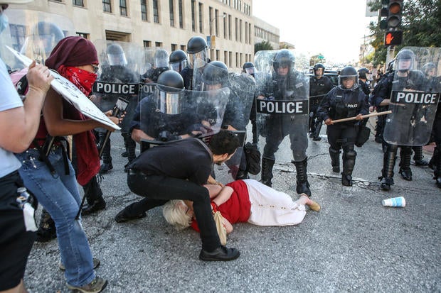 A woman who was pushed down by police is helped by a protester while police try to desperse a crowd, after a not guilty verdict in the murder trial of Jason Stockley in St. Louis