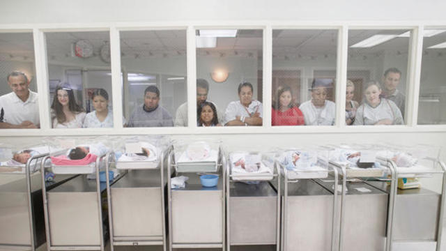 New parents watching babies in hospital nursery 