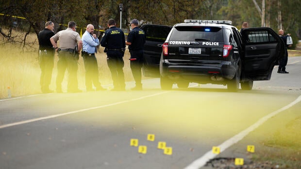Law enforcement officers and investigators converse near a police vehicle that was involved in a shooting on Nov. 14, 2017, in Rancho Tehama, California.