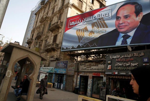 People walk by a poster of Egypt's President Abdel Fattah al-Sisi from the campaign titled “Alashan Tabneeha” (So You Can Build It), for the upcoming presidential election in Cairo