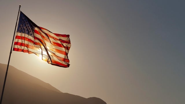 Back-lit American flag flying on pole with copy space. 