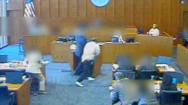 In this image capture from video provided to CBS Salt Lake City affiliate KUTV, Siale Angilau, center, rushes the witness stand in a federal courtroom in 2014. 