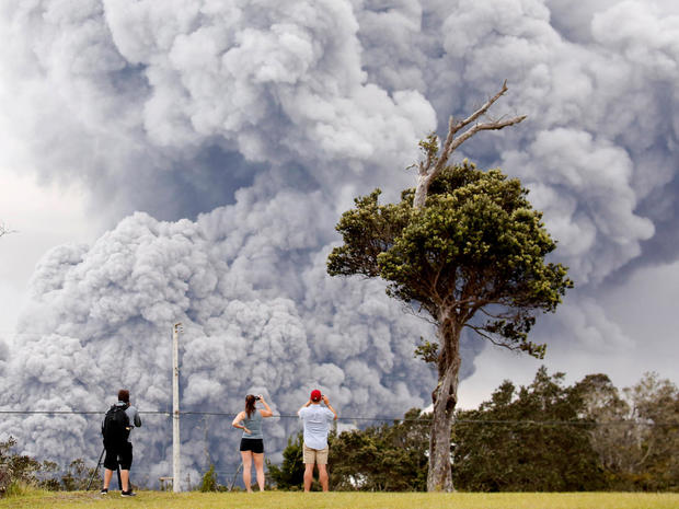 People watch as ash erupts from the Halemaumau crater near the community of Volcano 