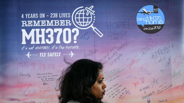A woman walks past a banner bearing solidarity messages for passengers of the missing Malaysia Airlines Flight 370 during a memorial event in Kuala Lumpur on March 3, 2018, ahead of the fourth anniversary of the ill-fated plane's disappearance.