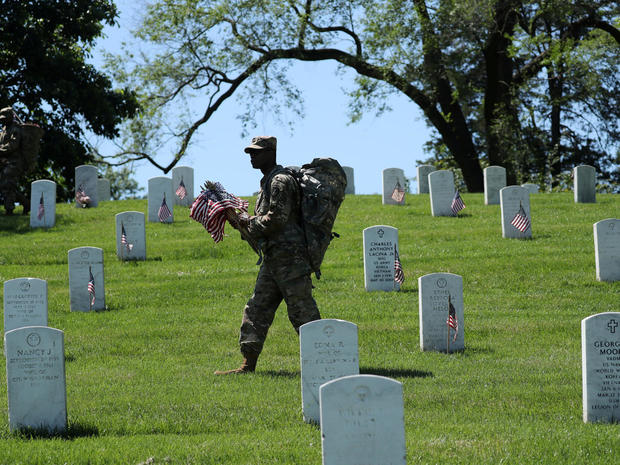 A U.S. Army soldier of the 3rd United States Infantry Regiment places U.S. flags on graves at Arlington National Cemetery 