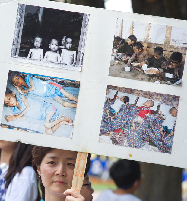 A woman holds up a poster with photos fr 