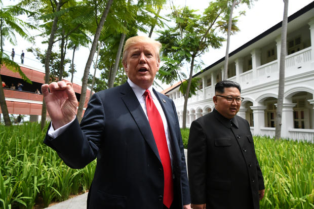 U.S. President Donald Trump gestures as he walks with North Korean leader Kim Jong Un in the Capella Hotel after their working lunch, on Sentosa island in Singapore 