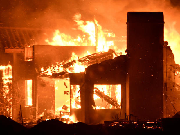 A house burns as firefighters battle flames at a home at the site of a wildfire in Goleta 