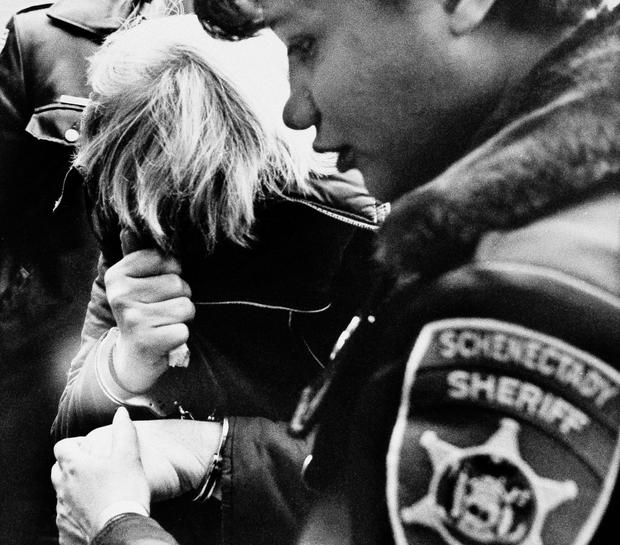 Marybeth Tinning, suspected by Schenectady police of killing the nine children in her care since 1972, covers her face while being escorted by a Schenectady County sheriff's deputy to court for a preliminary hearing on Feb. 11, 1986. 