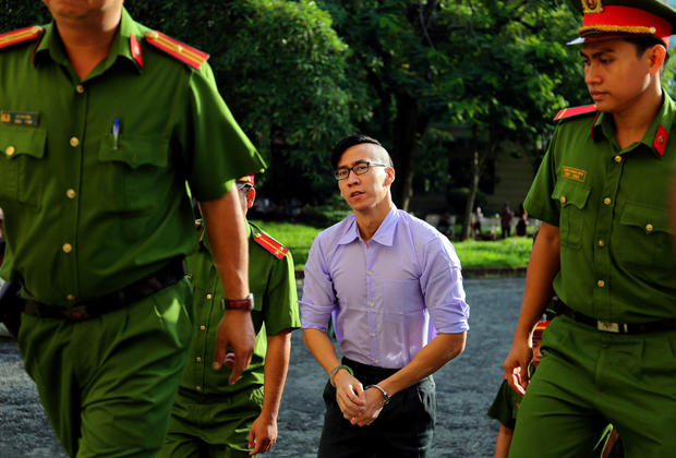 U.S. citizen Will Nguyen is escorted by police before his trial at a court in Ho Chi Minh city 