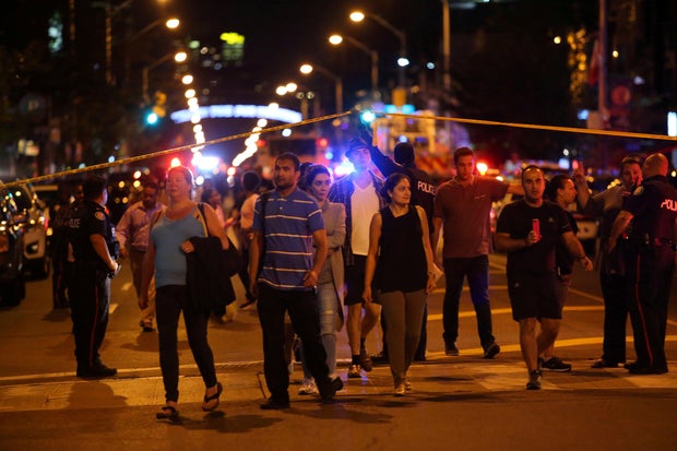 People leave an area taped off by the police near the scene of a mass shooting in Toronto 